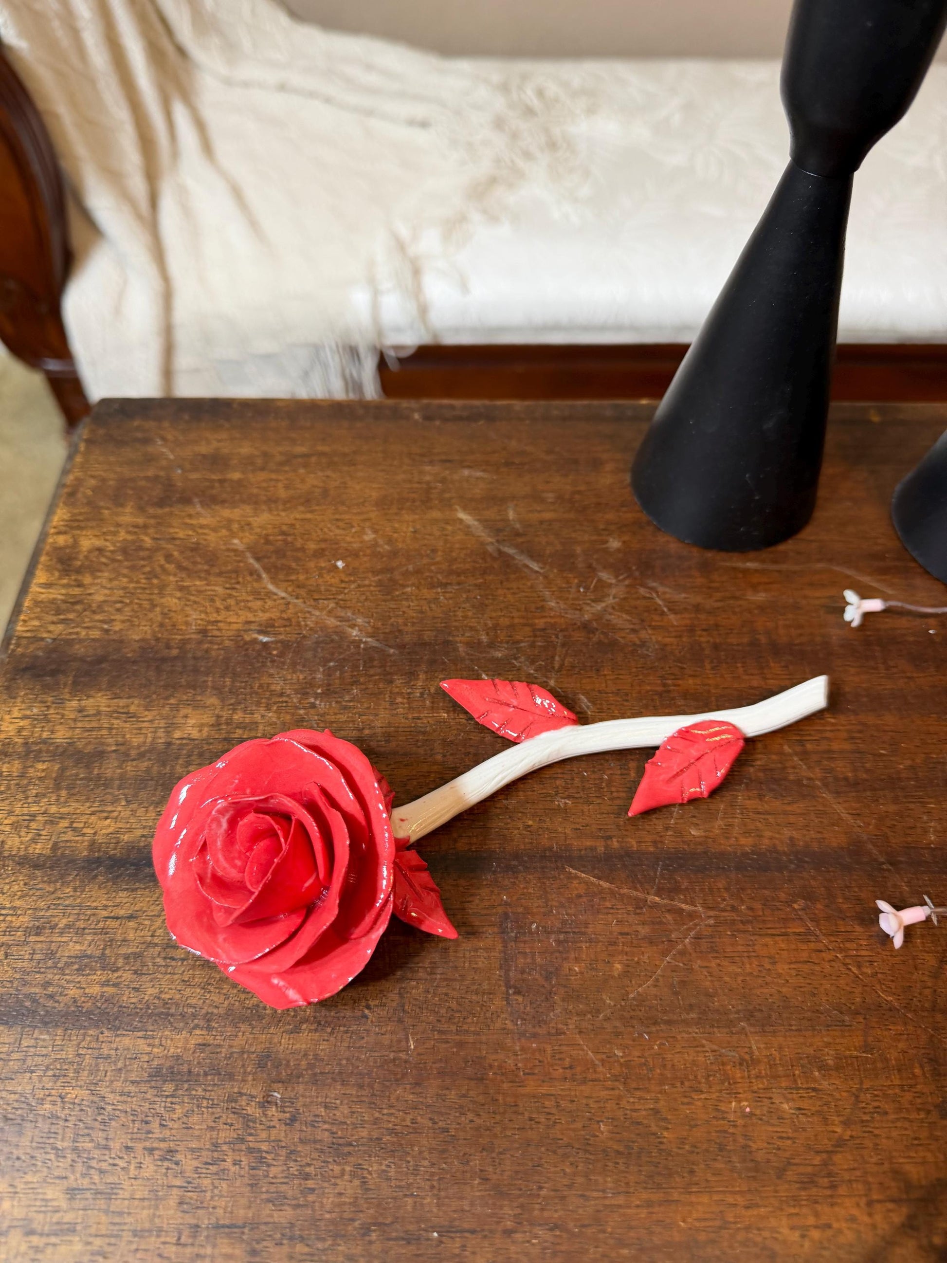 Red rose-shaped object on a wooden surface with a blurred background