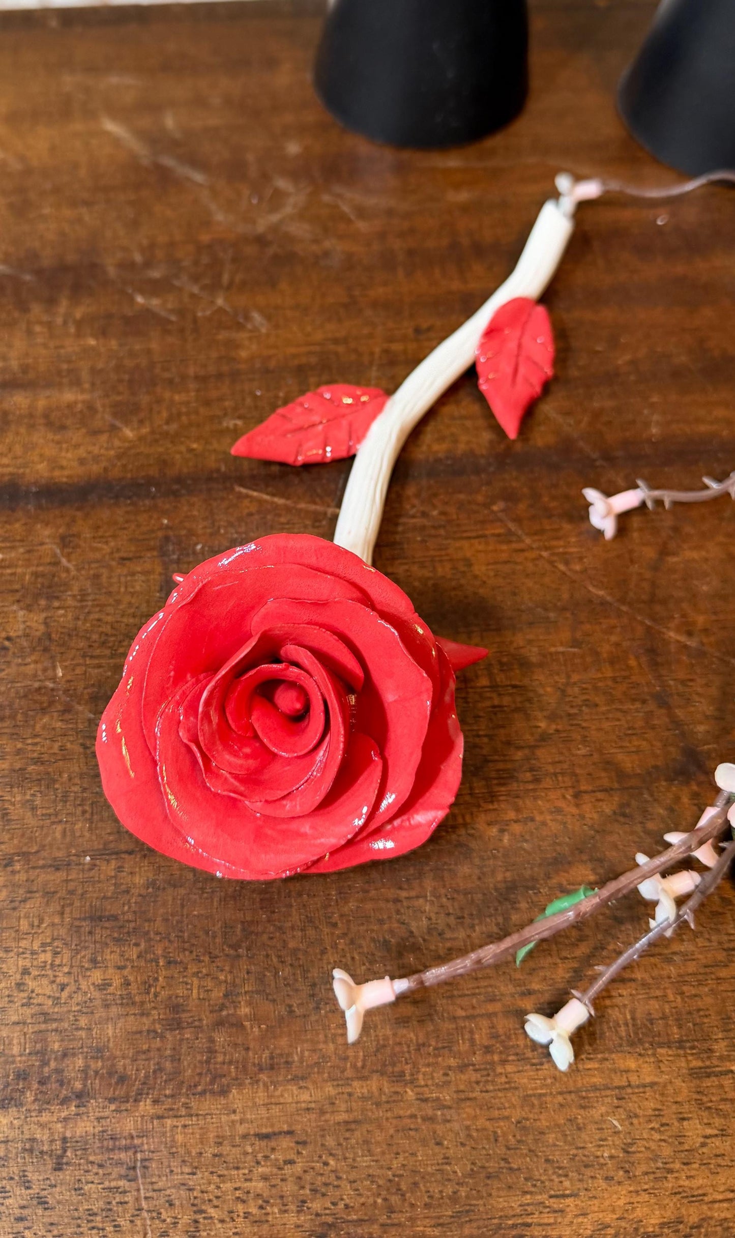 Red rose with a white stem on a wooden surface