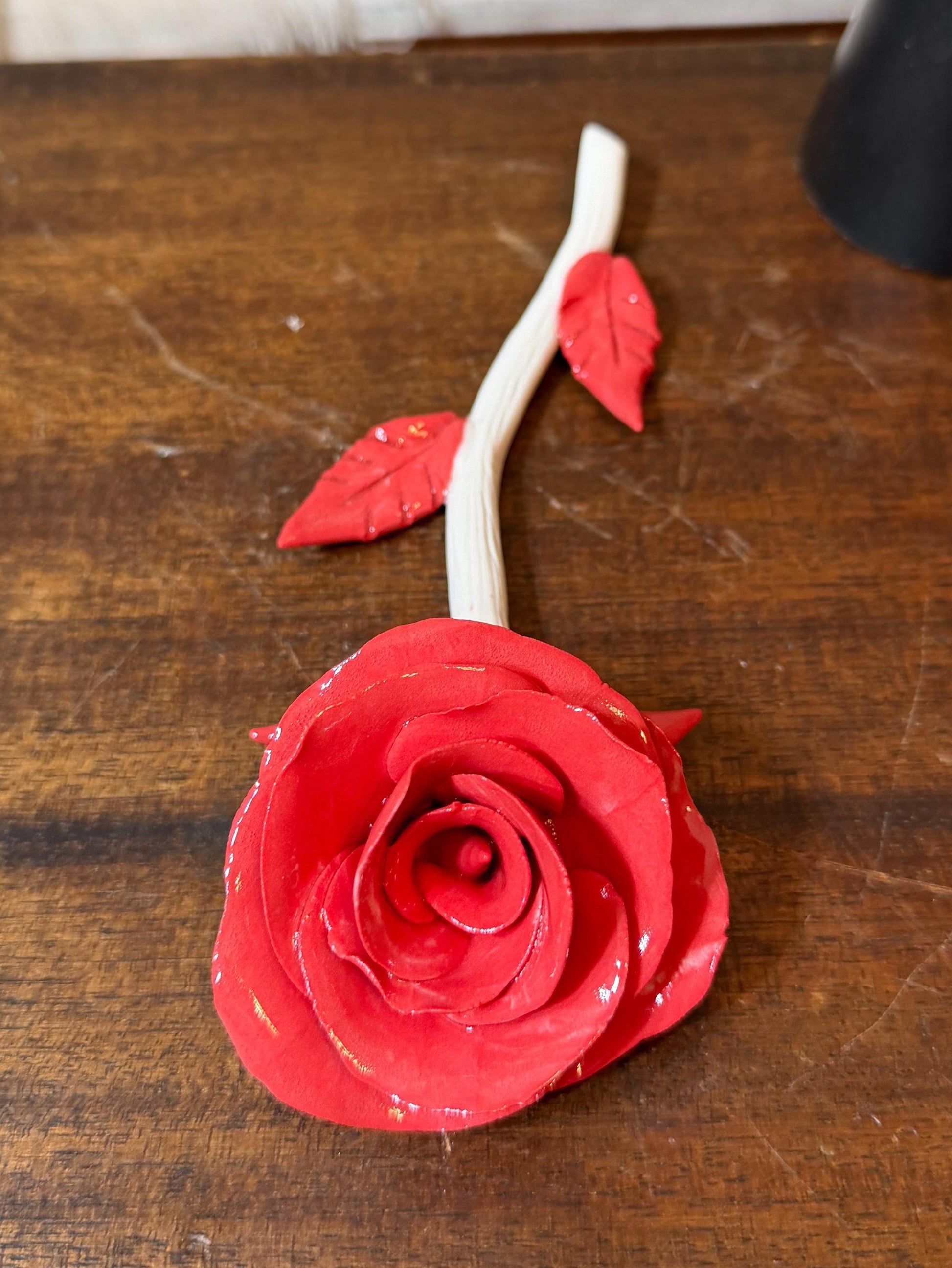 Red rose with a white stem on a wooden surface
